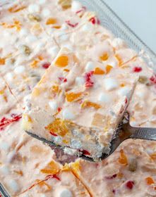 a close up of a dessert on a plate with a spoon in it and fruit toppings