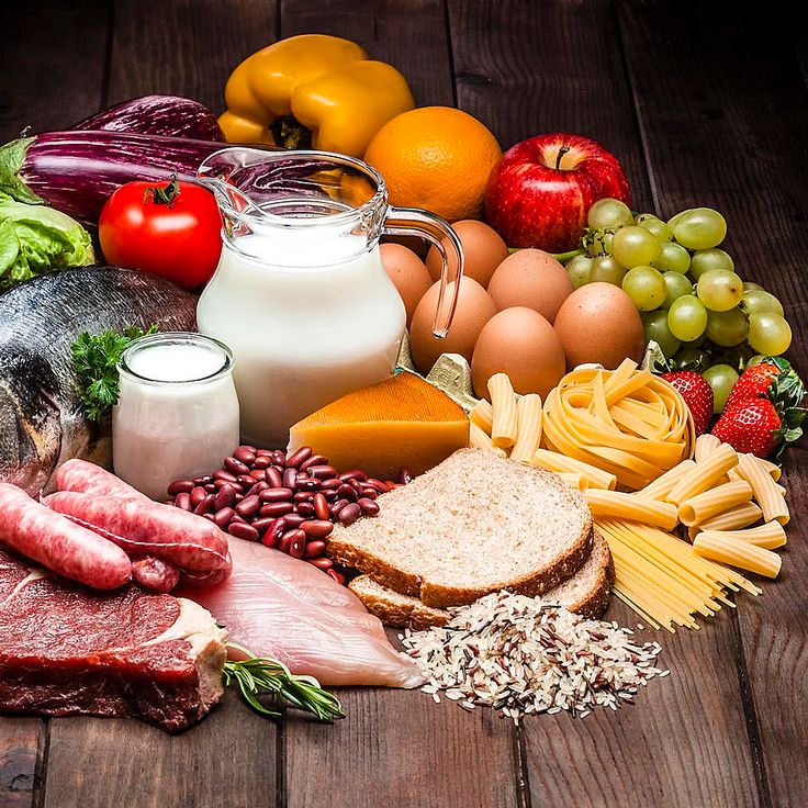 an assortment of food including meat, cheese, eggs, fruit and milk on a wooden table