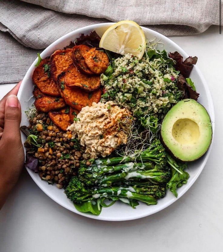 a white plate topped with lots of food next to an avocado and lemon wedge