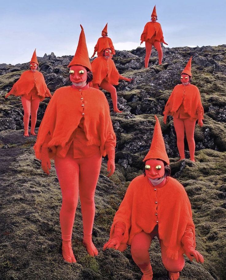 a group of people dressed in red standing on top of a grass covered hill next to each other