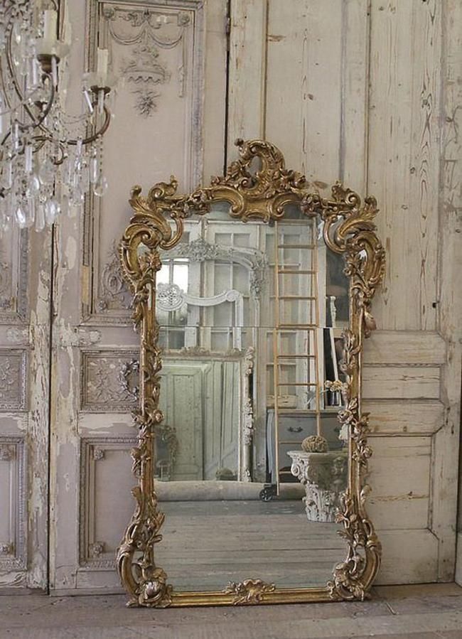 an ornate gold framed mirror sitting in front of a white wall with peeling paint on it