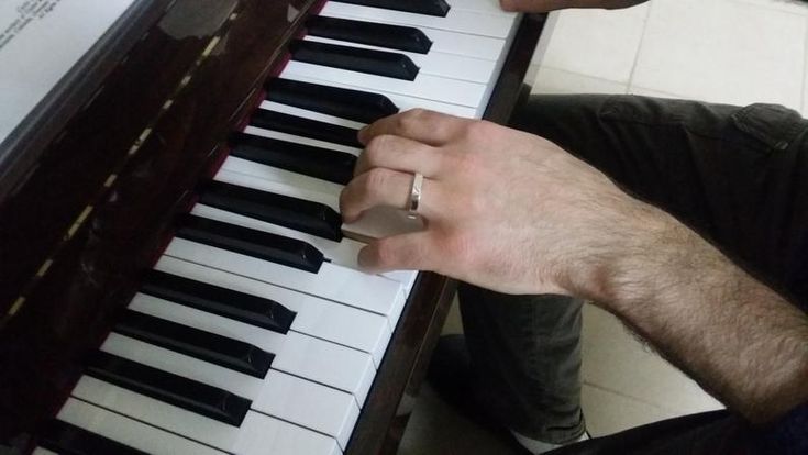 a man sitting at a piano with his hands on the keys and fingers resting on the keyboard