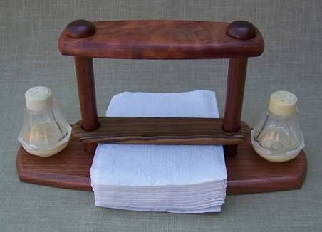 a wooden stand with napkins and two glass bottles on the top, sitting next to each other