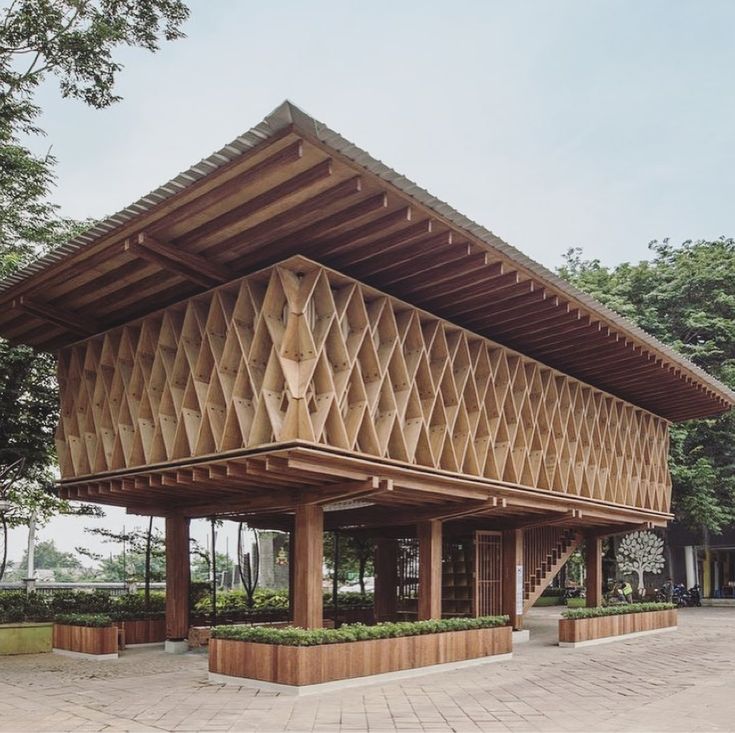 a wooden structure sitting on top of a brick floor next to tall grass and trees