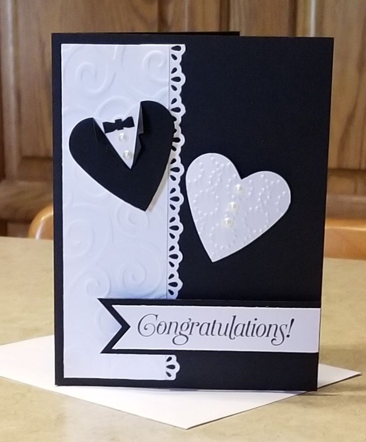 a congratulations card with two hearts and a bow on the front, sitting on top of a table