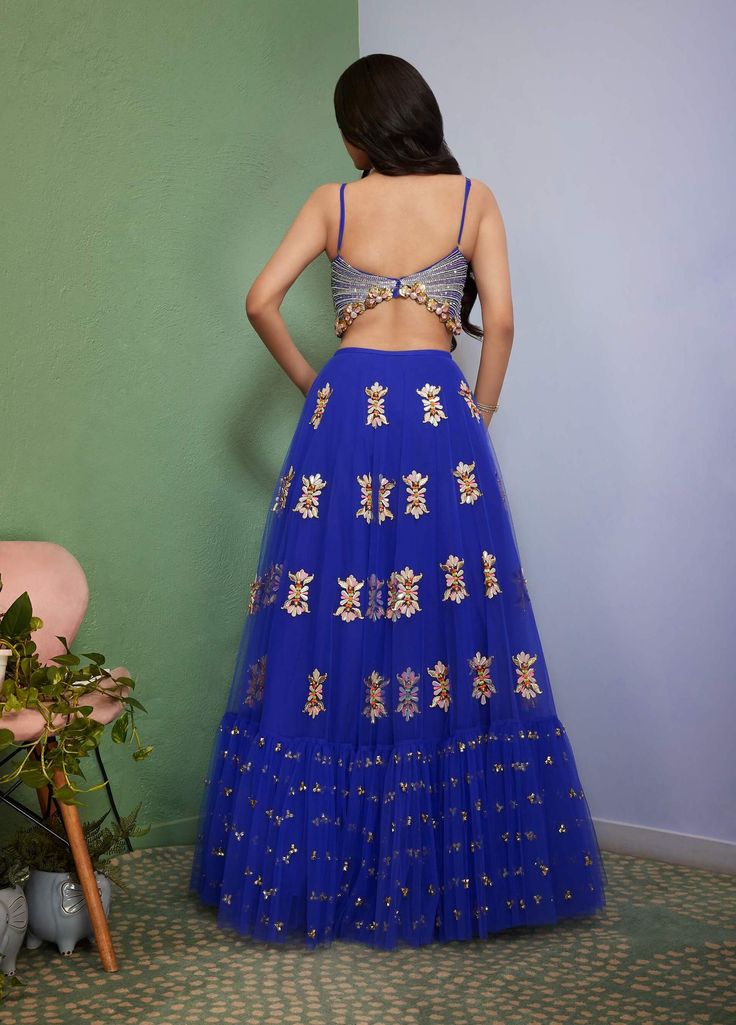 Editor's Note Introducing Artworq, a stunning iris blue lehenga designed to make you feel like royalty on your special day. Exquisitely crafted from a soft tulle base and embellished with shimmering glass crystals and intricate glass-cut beaded embroidery. The matching blouse features a stylish and modern cut, the piece comes with a matching dupatta, adorned with glass crystals and glass-cut beaded embroidery. Color: Blue Fabric: Tulle Neckline: V-neck Sleeve type: Sleeveless Embroidery details: Blue Fitted Anarkali Set For Party, Blue Party Dress With Dori Work, Blue Gown With Dori Work For Reception, Blue Designer Lehenga For Party Wear, Designer Resham Embroidery Skirt Set For Party, Hand Embellished Floor-length Sharara For Party, Hand Embellished Floor-length Party Wear Sharara, Designer Floor-length Skirt Set For Party Wear, Blue Party Wear Lehenga With Dori Work