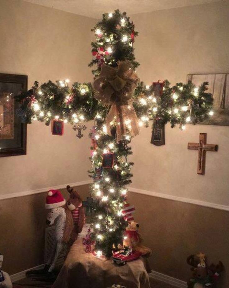 a cross decorated with christmas lights in a living room next to other decorations and toys