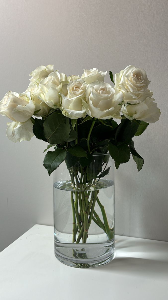 a vase filled with white roses on top of a table