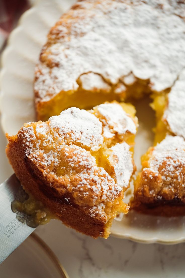 a piece of cake on a plate with a knife in it and powdered sugar on top