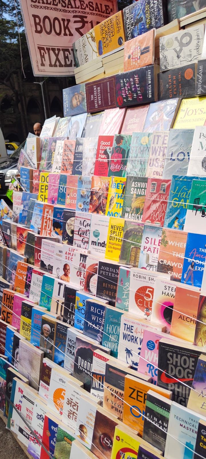 many books are stacked on top of each other in front of a book sale booth