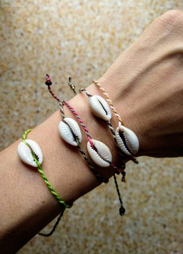 three seashell bracelets on someone's arm