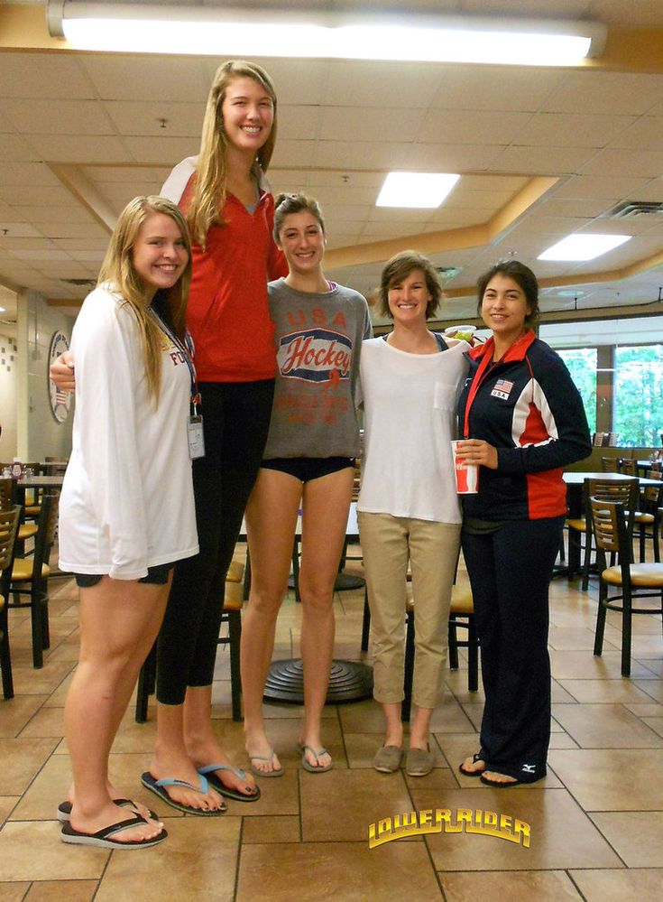 a group of women standing next to each other in front of a table with chairs