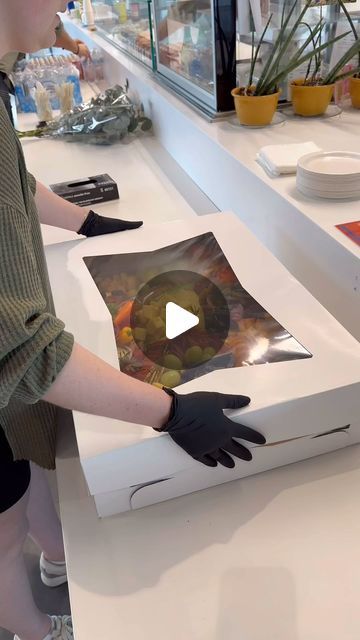 a woman in black gloves standing next to a white box with pictures on the side