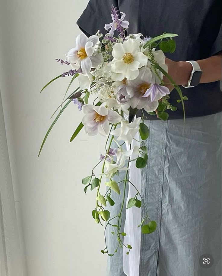 a man holding a bouquet of white and purple flowers