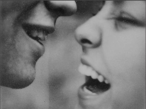 an old photo of two people with their mouths open and one is singing into the other's mouth