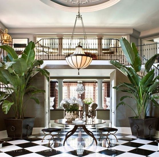 a foyer with black and white checkered flooring, potted plants and chandelier