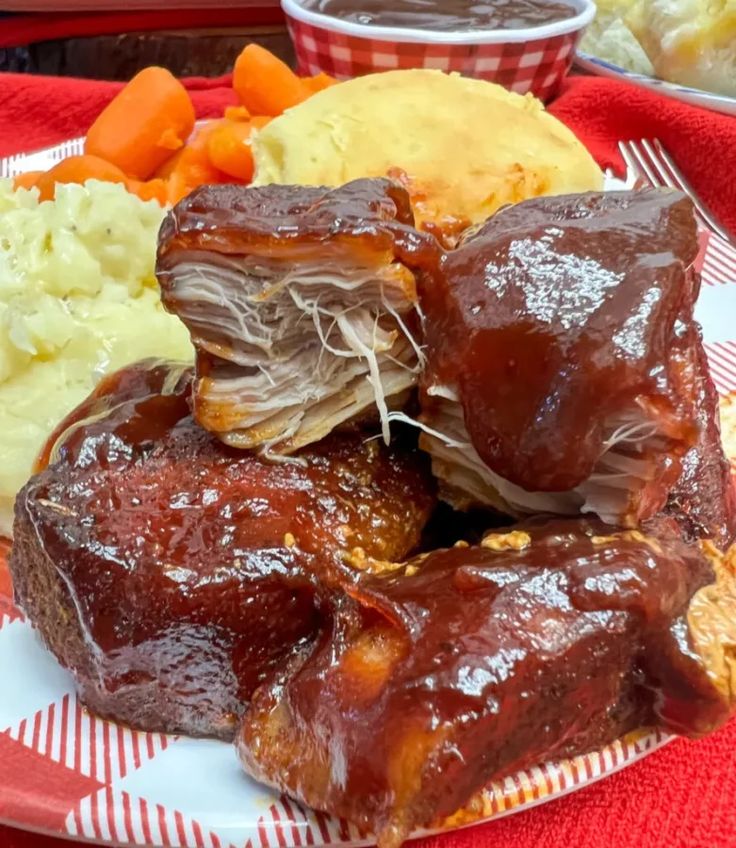 a plate full of ribs, mashed potatoes and carrots