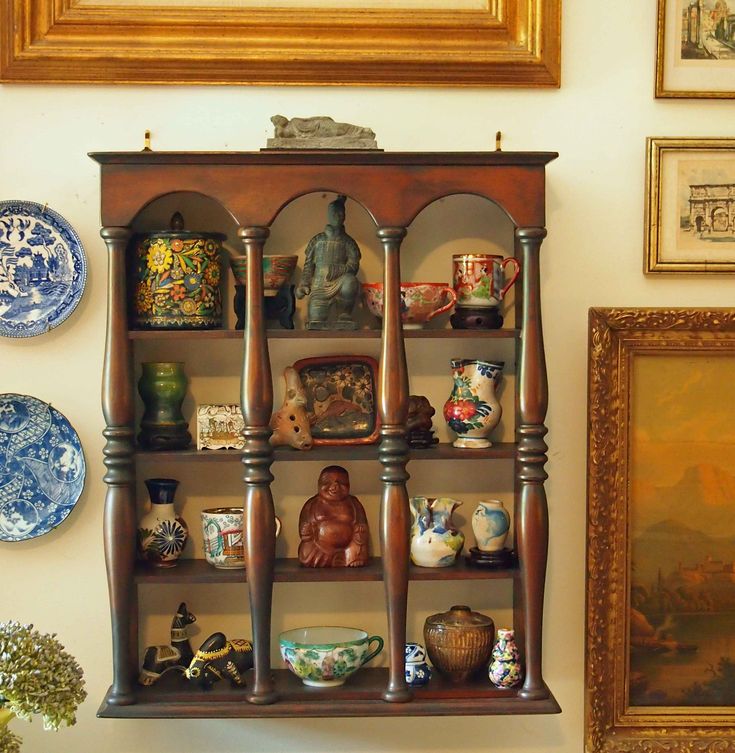 a wooden shelf filled with lots of vases and plates on top of a wall