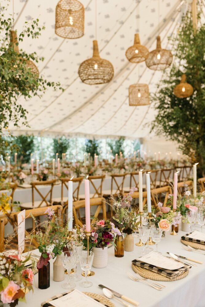 the tables are set with place settings and candles for an elegant wedding reception in a marquee