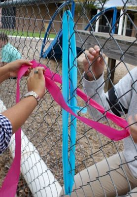 two children are playing with ribbons on a fenced in area at a park or playground