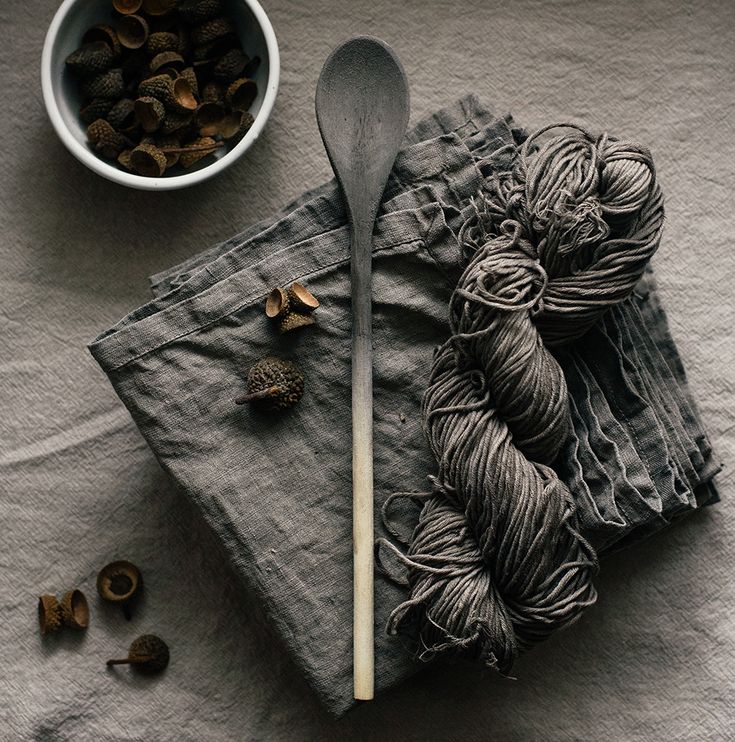 a bowl of nuts and a spoon on a napkin next to some skeins