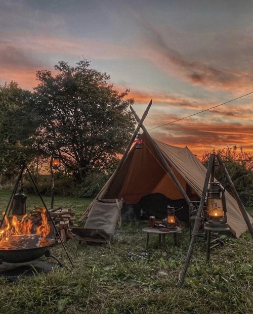 a tent is set up next to a campfire with candles in the foreground