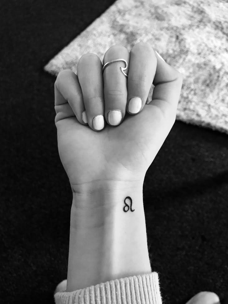 a woman's hand with a small tattoo on her wrist and the letter q