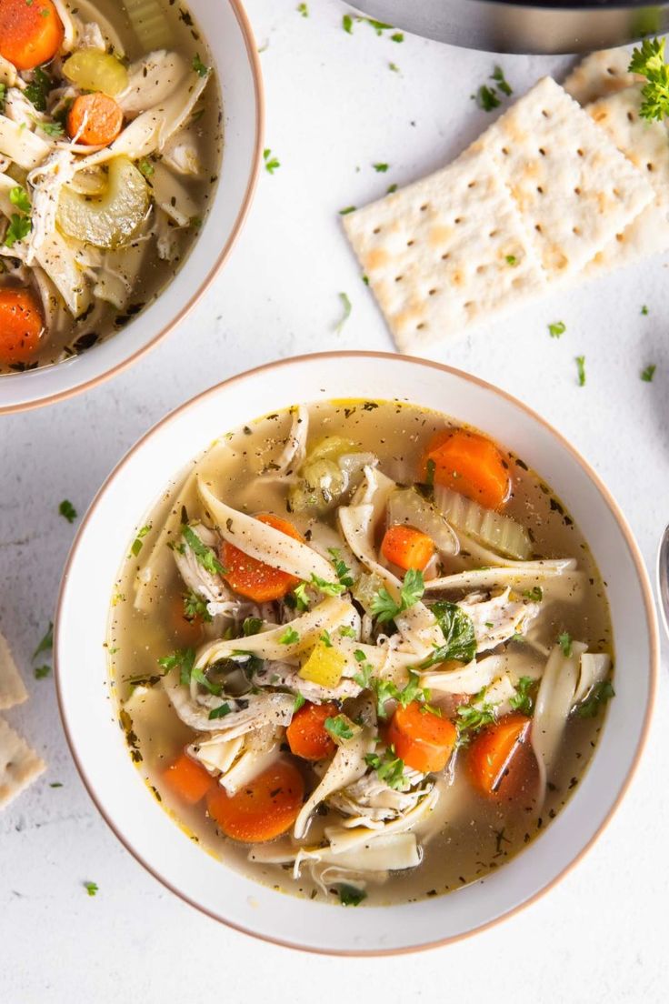 two bowls of chicken noodle soup with crackers