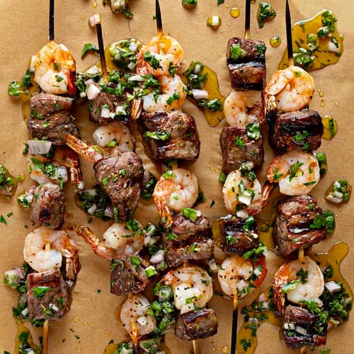 the skewers are covered with shrimp and garnished with parsley on top