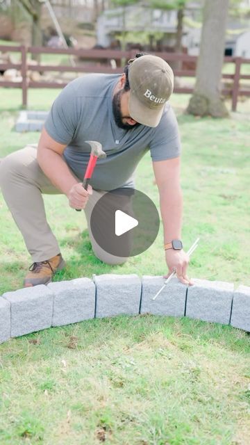 a man is building a fire pit in the yard with bricks and hammers on it