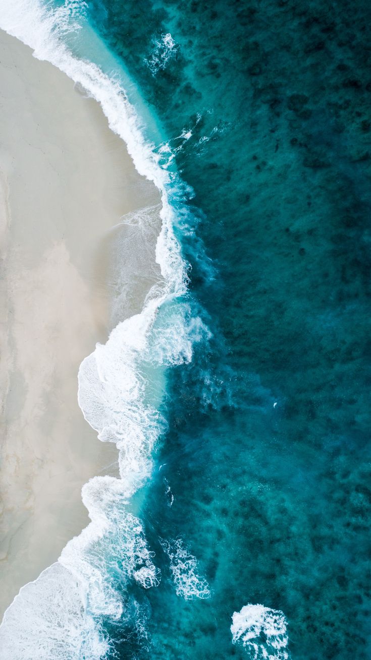 an aerial view of the beach and ocean with waves coming in from the sand, as seen from above