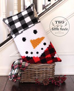 a knitted snowman pillow sitting on top of a basket next to a stair case