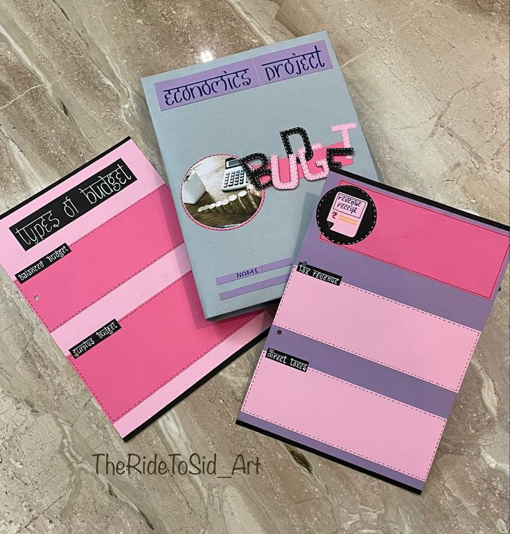 two notebooks sitting next to each other on top of a marble floor covered in pink and blue paper