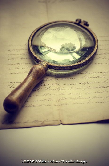 a magnifying glass sitting on top of an old piece of paper with writing underneath it