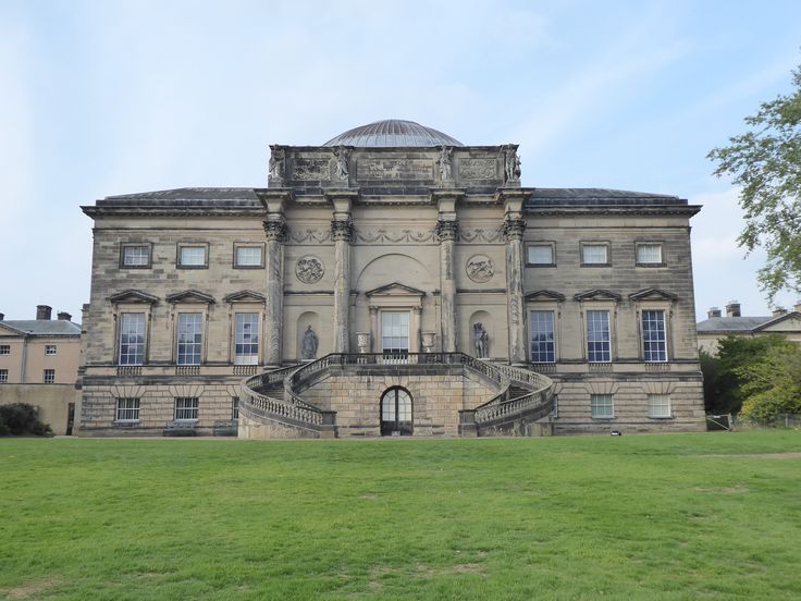 an old stone building with steps leading up to the front door and green grass in front of it