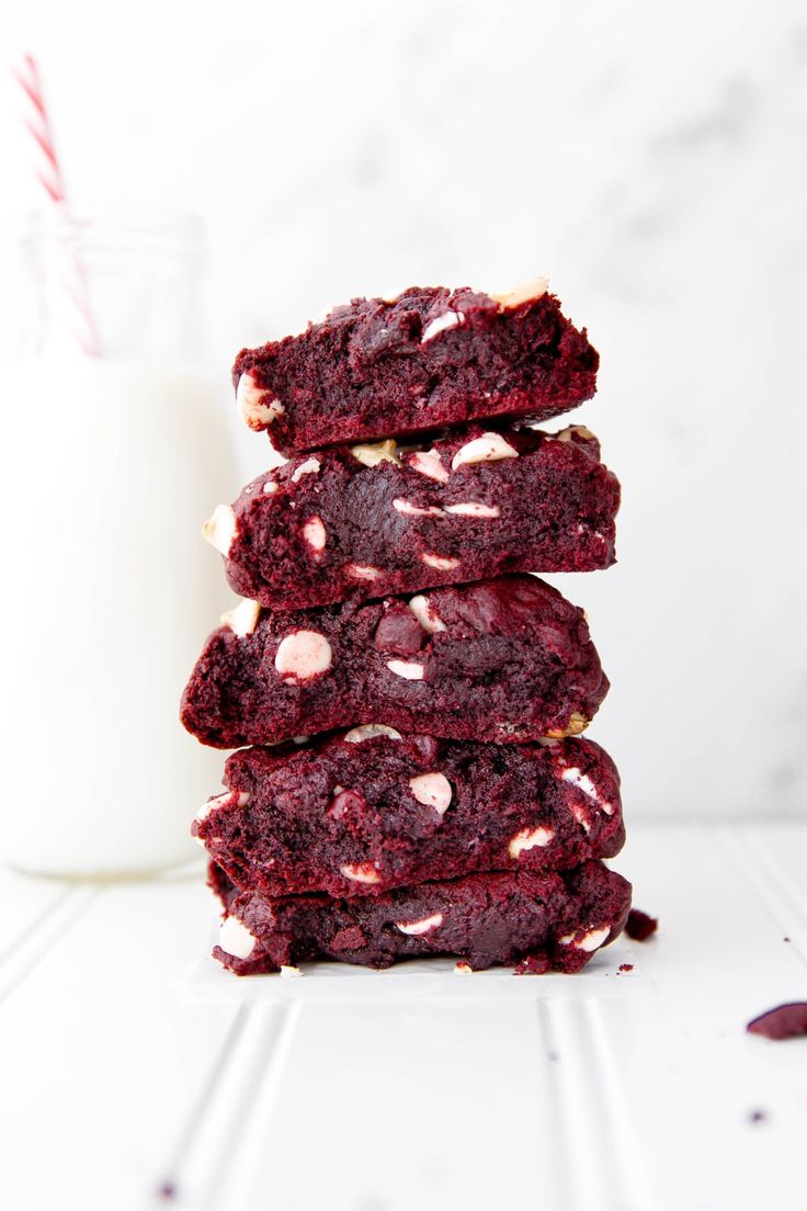 red velvet cookies stacked on top of each other next to a glass of milk and straw