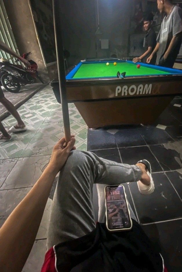 a man is playing pool on the floor with his cell phone in front of him