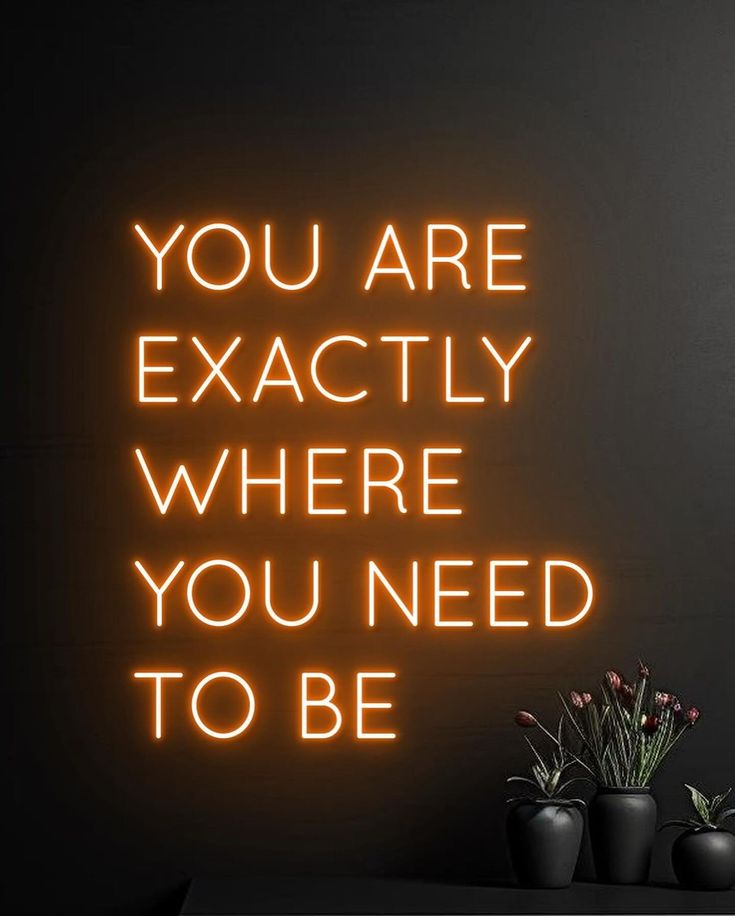 a neon sign that says you are exactly where you need to be on the wall