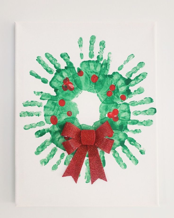 a handprinted christmas wreath is displayed on a white surface with red ribbon and green hands