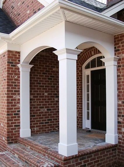 a brick house with white columns and an arched entryway leading to the front door