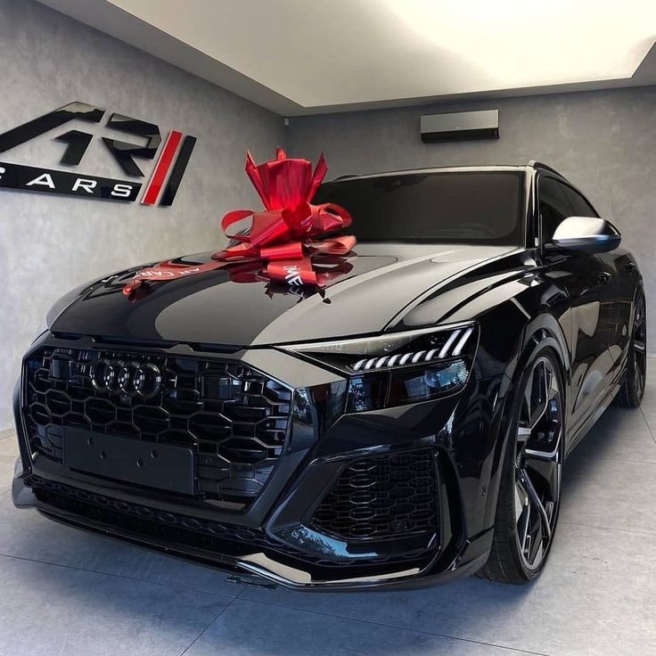 a black car with a red bow on it's hood in a showroom