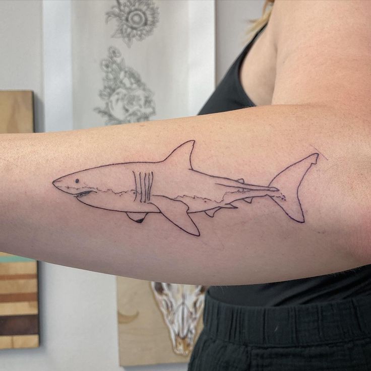 a woman's arm with a tattoo of a shark on the left side of her arm