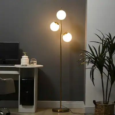 a living room with a computer desk, chair and lamp on the floor next to a potted plant