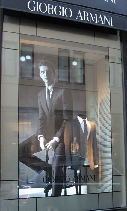 a window display with mannequins and suits on it's windowsill