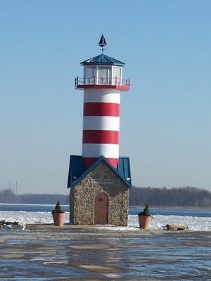 a red, white and blue light house sitting in the middle of snow covered ground