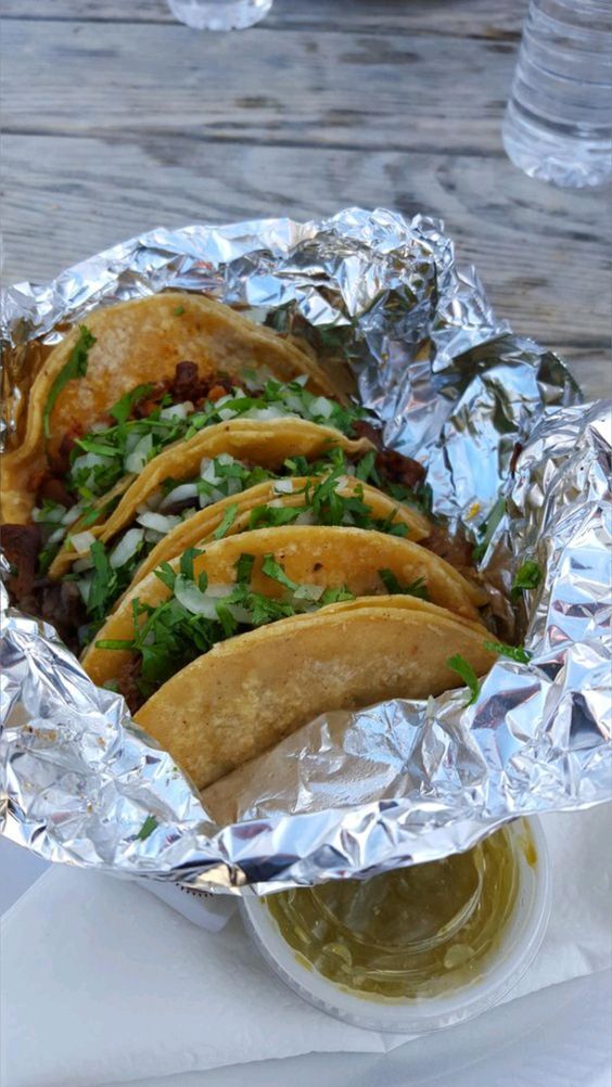 some tacos are wrapped in foil on a table