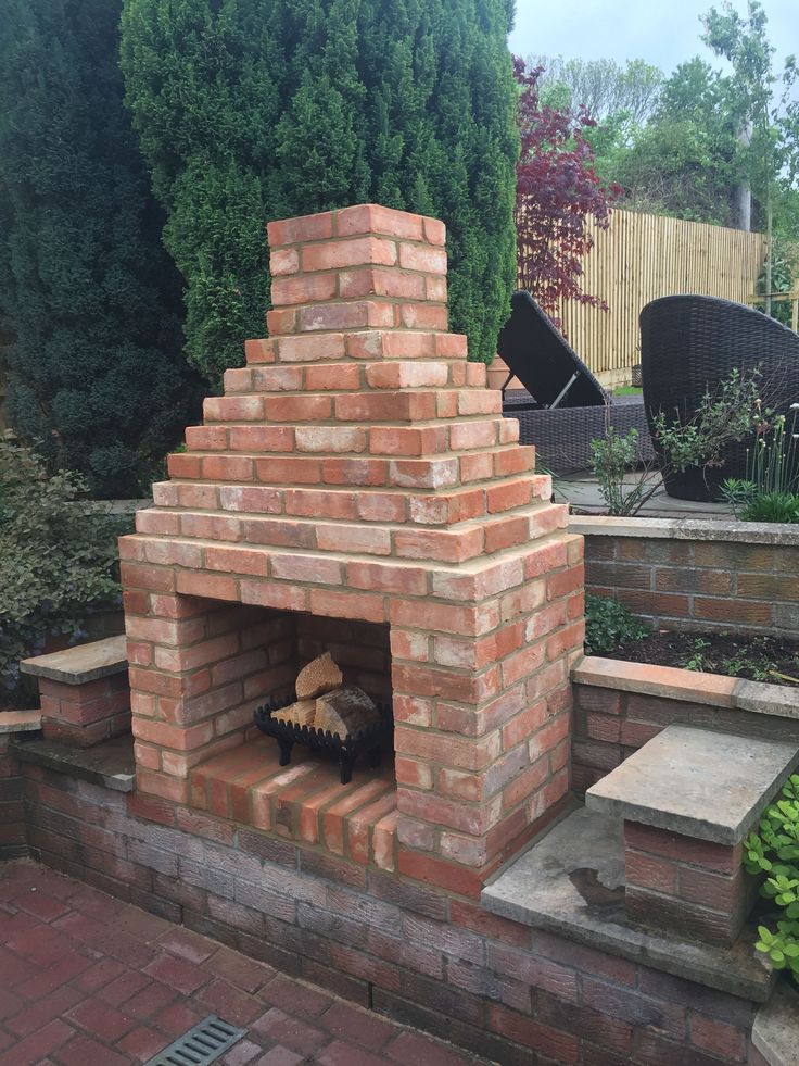 a brick oven sitting in the middle of a garden with steps leading up to it