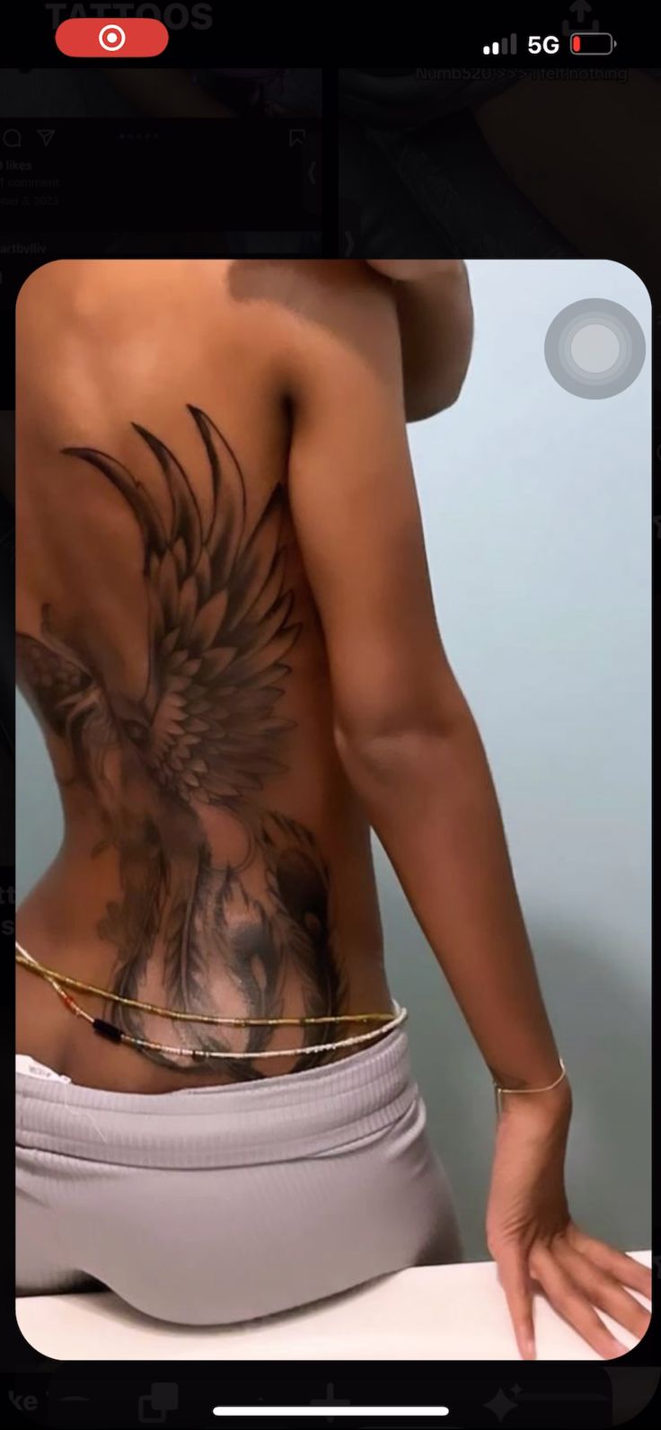 the back of a woman with tattoos on her body and hands in front of her stomach