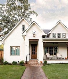 a white house with a brick walkway leading to the front door and covered porch area