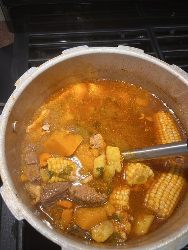 a pot filled with soup and corn on the cob